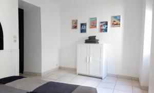 a white room with a cabinet and pictures on the wall at Charmante Maison dans petite citée de caractère 13km du ZOO in Luché-Pringé