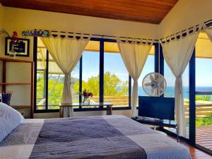 a bedroom with a bed and large windows at Santa Teresa Surf Vista Villas in Santa Teresa Beach