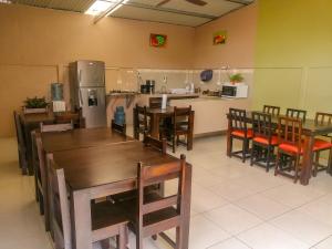a restaurant with wooden tables and chairs and a kitchen at Nice Place Hostel in Fortuna