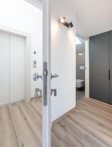 a bathroom with white walls and wooden floors and a sliding door at Hotel Canton dell'Orto in Padova