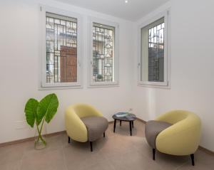 2 Stühle und ein Tisch in einem Zimmer mit Fenstern in der Unterkunft Hotel Canton dell'Orto in Padua