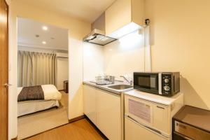 una pequeña cocina con fregadero y microondas en Stay SAKURA Nihonbashi / Vacation STAY 51029, en Osaka