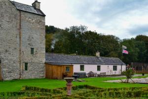 an old stone building with a flag in front of it at The Lady Maxwell Room at Buittle Castle in Dalbeattie