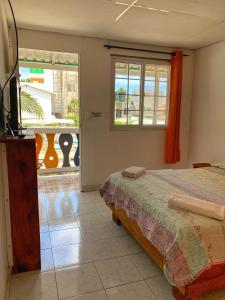 1 dormitorio con cama, TV y balcón en Posada Donde Pilo Avila, en San Andrés