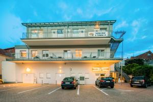 ein Gebäude mit einem Turm mit Autos auf einem Parkplatz in der Unterkunft Schäfers Hotel, Self Check In, Cafe am Hotel in Vechta