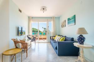 ein Wohnzimmer mit einem blauen Sofa und einem Tisch in der Unterkunft Sun & Sand Beach Apartment in Marbella