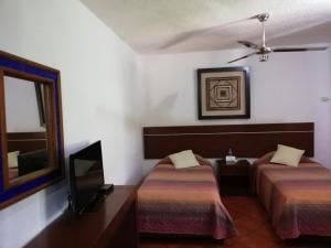 a hotel room with two beds and a tv at Hotel Los Girasoles in Cancún