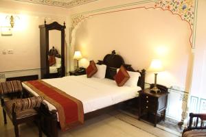 una camera con un grande letto e uno specchio di WelcomHeritage Traditional Haveli a Jaipur