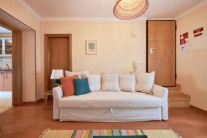 een woonkamer met een witte bank en kleurrijke kussens bij Spacious and Renovated Apartment With Amazing Patio, By TimeCooler in Lissabon