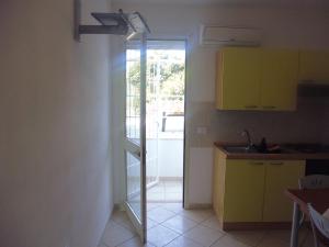 une cuisine avec des armoires jaunes et une porte donnant sur une cour dans l'établissement Residence Rivamare Ugento, à Torre Mozza