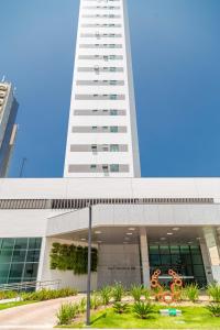 a tall white building with a sculpture in front of it at Beach Class, Ilha do Leite, Flat completo 1406 in Recife