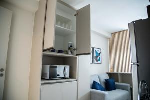 a small kitchen with a microwave and a couch at Beach Class, Ilha do Leite, Flat completo 1406 in Recife