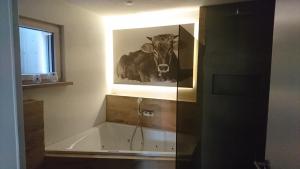 a painting of a cow is on the wall of a bathroom at Kuhnest in Scheidegg