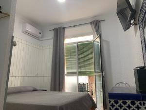 sypialnia z łóżkiem i oknem w obiekcie Hostal Alcobia w Sewilli