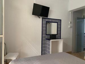 sypialnia z lustrem i telewizorem na ścianie w obiekcie Hostal Alcobia w Sewilli +37 zdjęć