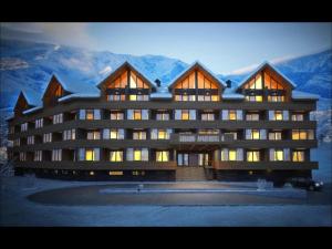 a large building with mountains in the background at Apartment Mountain Orchid in Gudauri