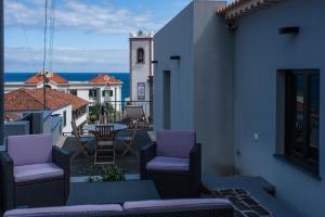 a balcony with purple chairs and a clock tower at Casa Abreu in Ponta Delgada