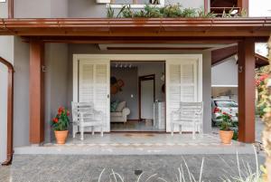 Casa Paradisíaca na Lagoa da Conceição في فلوريانوبوليس: شرفة مع كراسي بيضاء وأريكة