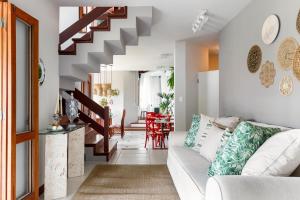 uma sala de estar com um sofá branco e escadas em Casa Paradisíaca na Lagoa da Conceição em Florianópolis