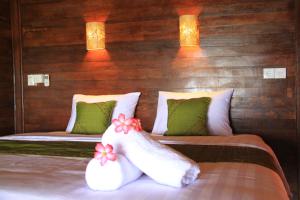 a bedroom with two beds with green and white pillows at Twilight Ceningan in Nusa Lembongan