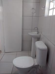 a white bathroom with a toilet and a sink at Chalé Excelente Localização in Ubatuba