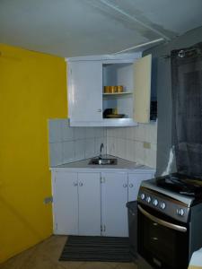 a kitchen with white cabinets and a sink and a stove at Ocean View - 1Bedroom overlooking the sea in Cane River +3 photos