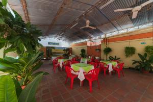 un restaurante con sillas rojas, mesas y plantas en Hotel Olimpico, en Barranquilla