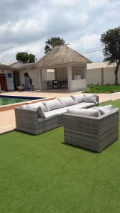 a group of couches sitting on the grass near a pool at Residence 21 in Kololi