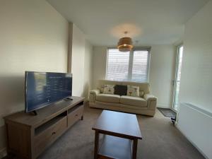 sala de estar con TV y sofá en Central Milton Keynes hub one bedroom secured apartment, en Milton Keynes