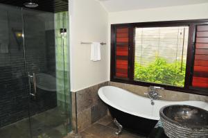 a bathroom with a tub and a glass shower at Crown Beach Resort & Spa in Rarotonga