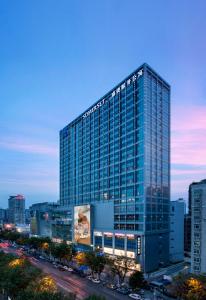 武漢的住宿－武漢盛捷武勝服務公寓，黄昏时在城市里建的一座高大的玻璃建筑