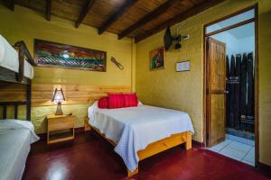 1 dormitorio con 1 cama con almohadas rojas en Kimbas Bungalows Mancora, en Máncora