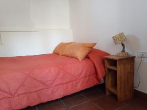 un letto con piumone rosso e una lampada su un tavolo di La Casa de Violeta a Tilcara