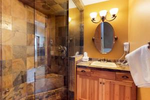 a bathroom with a shower and a sink and a mirror at Glacier Lodge 106 in Big White