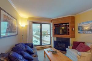 a living room with a couch and a tv at Snow Ghost Inn 326 in Big White