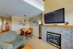 a living room with a fireplace with a flat screen tv at Trappers Crossing 28 in Big White