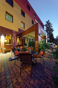 eine Terrasse mit Tischen und Stühlen vor einem Gebäude in der Unterkunft Hotel Max Inn in Bratislava