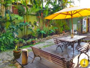 a wooden table and bench with an umbrella at Pousada Solar do Algarve em Paraty há 5 minutos do Centro Histórico in Paraty