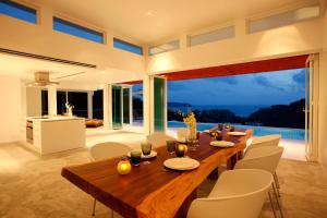 a dining room with a wooden table and white chairs at Tian Blue Villa in Kamala Beach