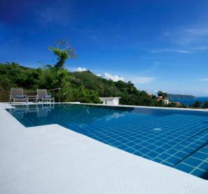 a swimming pool with a view of the ocean at Tian Blue Villa in Kamala Beach