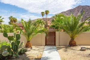 a house with palm trees and a fence at tHe PRESIDENTIAL HOUSE: EXCLUSIVE MOUNTAIN VIEWS & AMENITIES in La Quinta