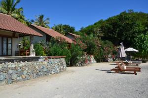 a beach with chairs and an umbrella and a building at Cocotinos Sekotong Lombok in Sekotong