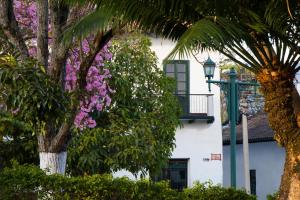 a white building with trees and purple flowers at El Portón de Enriqueta in Guaduas