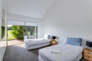 a bedroom with two beds and a sliding glass door at Cape Schanck Golf Getaway in Cape Schanck