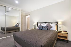 1 dormitorio con 1 cama grande y espejo en Wollongong Serviced Apartments, en Wollongong