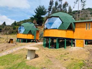 two houses with green roofs sitting on a hill at Glamping Los Balcones in Cuítiva