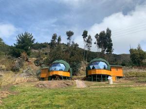 2 tentes vertes et oranges dans un champ dans l'établissement Glamping Los Balcones, à Cuítiva