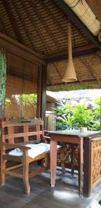 a table and a bench on a patio with plants at IDA'S Homestay in Candidasa