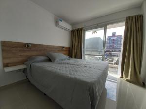 a bedroom with a bed and a large window at Edificio Leonardo, 5to piso in Villa Carlos Paz