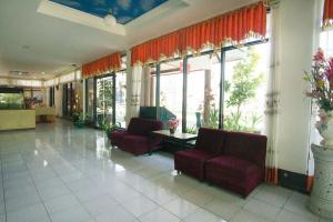 a lobby with two red chairs and windows at RedDoorz plus near Pelabuhan Bitung in Bitung